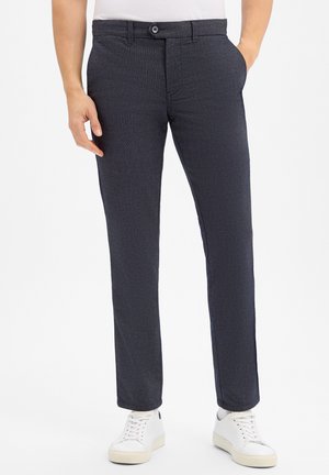 Donkergrijze stoffen broeken met een subtiel textuurpatroon, voorzien van een knoopsluiting, riemlussen en zijzakken, gecombineerd met witte sneakers.