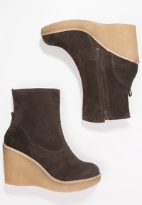 Brown suede wedge ankle boots with a side zipper, rounded toe, and textured light brown platform sole. Smooth, soft surface with stitching details.