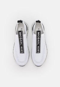 Bílé slip-on tenisky s prodyšným svrškem, černobílým logo páskem a texturovanou podrážkou. Kulatý design špičky, minimalistický styl.