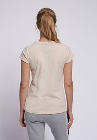 Camiseta de algodón rosa claro con mangas cortas y cuello redondo, que presenta una textura suave y un diseño ajustado.