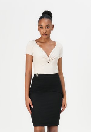 Haut ajusté beige avec un design twist à l'avant, manches courtes. Jupe crayon noire avec une finition texturée et un accent en argent à la taille.