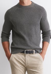 Šedý žebrovaný svetr s kulatým výstřihem, s dlouhými rukávy a texturovaným vzorem. Kombinován s lehce béžovými manšestrovými kalhotami a černým pásem.