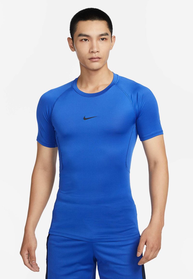Blå kortermet treningsskjorte laget av elastisk stoff. Har rund hals og svart Nike-logo på brystet. Glatt tekstur.