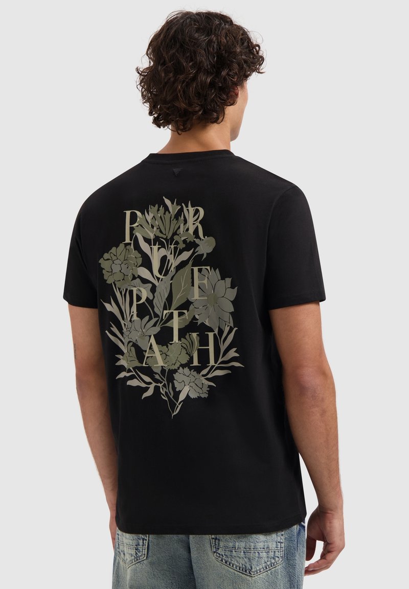 Zwarte katoenen T-shirt met een grote bloemenafbeelding in gedempte groene tinten op de achterkant, met de tekst "RSPB PATH" geïntegreerd in het ontwerp.