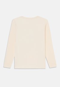 Dlouhý rukávový top z měkké krémové látky s kulatým výstřihem, jednoduchým, nezdobeným designem a rovně střiženým lemem.
