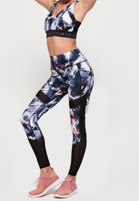 Set sportivo composto da un reggiseno sportivo nero e blu con una fascia larga, abbinato a leggings a vita alta con pannelli in rete e dettagli rosa.