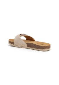 Beige suède slipper sandaal met een kurken zool, met een gebogen band ontwerp en kleine gouden hardware accenten langs de rand.