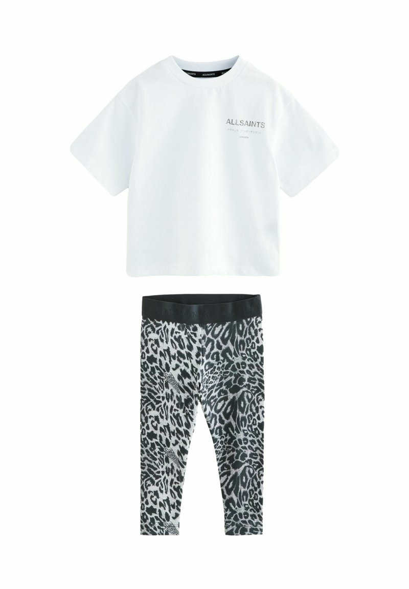 Bijela pamučna majica s "ALLSAINTS" logom na prsima; uparena s crnim i sivim tajicama s printom leoparda koje imaju široki crni pojas.