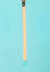 Jasnoniebieska bluza na zamek z delikatnie fakturowanego materiału, kontrastującym żółtym zamkiem oraz wysokim kołnierzem. Idealna do aktywności fizycznej.