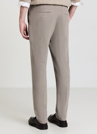 Pantalon gris clair avec un motif texturé, coupe droite, deux poches arrière, porté avec des chaussures noires sur un fond uni.