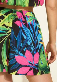 Krótkie, elastyczne szorty z żywym tropikalnym wzorem w różowe, zielone i niebieskie liście na czarnym tle. Gładka faktura, casualowy design.