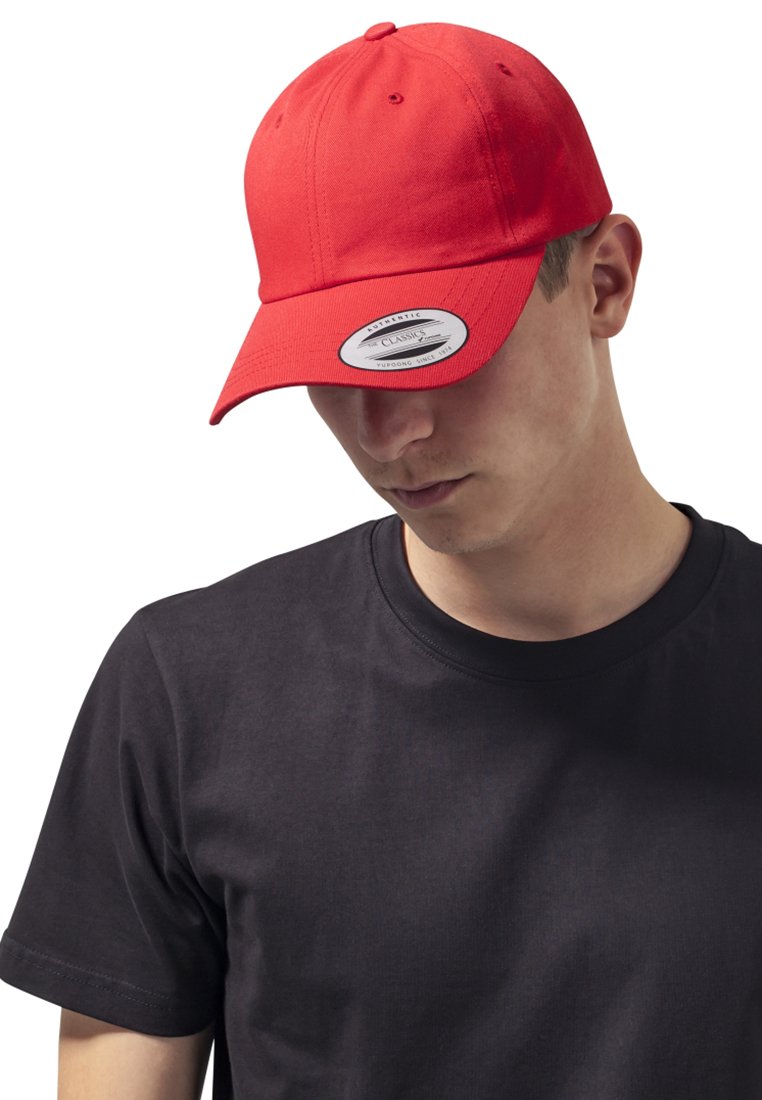 Rode baseballpet met een gebogen klep. De stof is glad met stiksels en een verstelbare band. Gedragen met een simpele zwarte T-shirt.