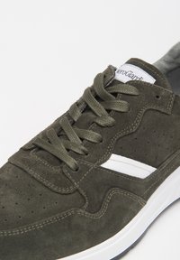 Sneaker verde in suede con striscia bianca a contrasto, design con lacci, dettagli perforati e suola texturizzata.