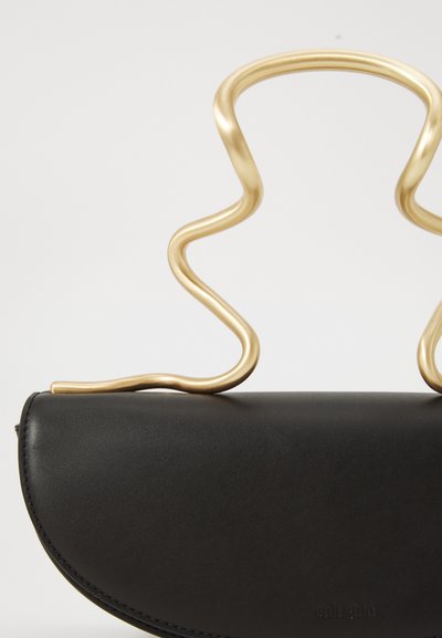 Bolsa de couro preto com uma alça em metal dourado curvada, apresentando um design ondulado. Superfície texturizada com detalhes de costura sutis.