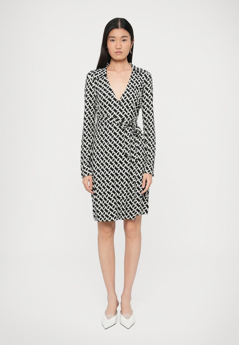 Μαύρο και άσπρο φόρεμα τύπου wrap με μακριά μανίκια, γεωμετρικό μοτίβο αλυσίδας, βαθύ V-λαιμόκοψη και δεμένη λεπτομέρεια στη μέση.