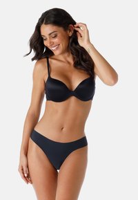 Reggiseno nero e bikini abbinato realizzati in tessuto morbido. Il reggiseno presenta una scollatura profonda e spalline regolabili.