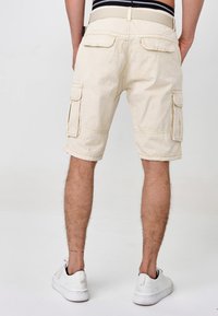 Beige Cargo-Shorts mit zwei seitlichen Taschen, einem Stoffgürtel und einem umgeschlagenen Saum. Hergestellt aus strapazierfähigem Material, geeignet für die Freizeit.