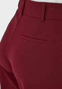 Bordo krojene hlače glatke teksture, s jednim stražnjim džepom i strukturiranim dizajnom struka.