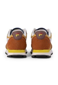 Brune og orange sneakers med en tekstureret ruskindsfinish, der har et hvidt logo, gule accenter på sålen og et forstærket hældesign.