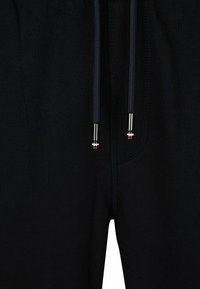 Zwarte joggingsbroek met een ribbelstructuur, elastische tailleband en trekkoorden met metalen uiteinden. Inclusief voorzakdetail.