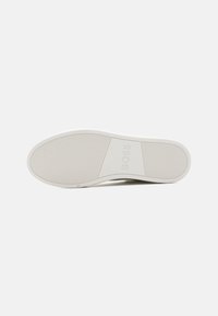 Semelle de chaussure en caoutchouc blanc, plate avec des rainures horizontales. Logo "BOSS" embossé dans la zone de la voûte. Texture lisse, design minimaliste.