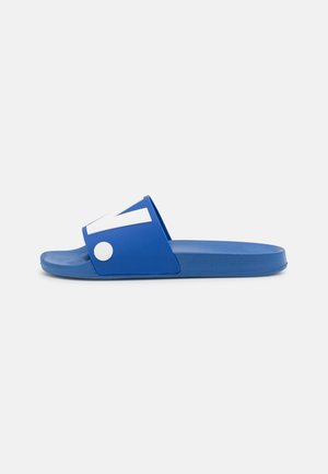 Blue slide sandal made of rubber. Features a wide strap with white accents and a textured sole, designed for comfort and stability.