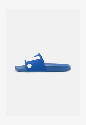 Blue slide sandal made of rubber. Features a wide strap with white accents and a textured sole, designed for comfort and stability.