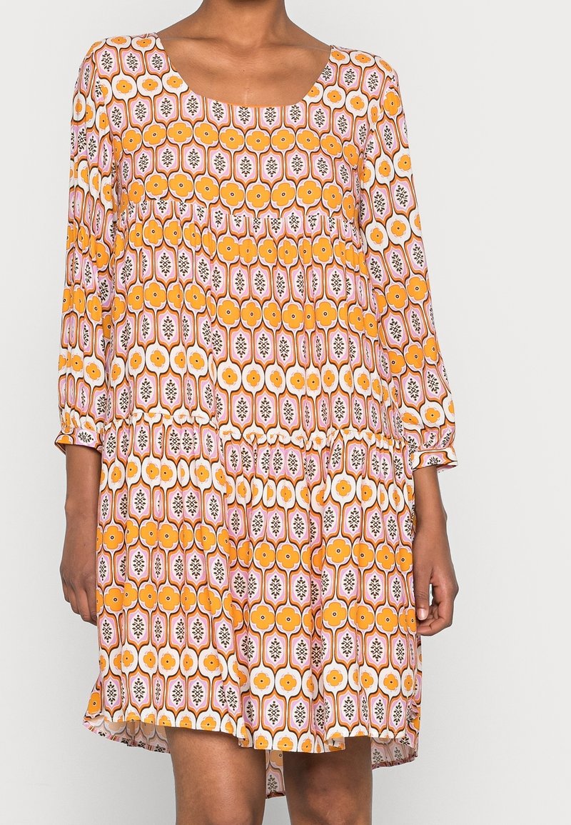 Oranje en roze gemarmerde jurk met driekwart mouwen, ronde halslijn en gepofte taille. Bevat bloemen- en geometrische ontwerpen.