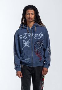 Navy zip-up hoodie with graphic designs of a serpent and octopus. Features a kangaroo pocket and contrasting logo text. Soft fabric texture.