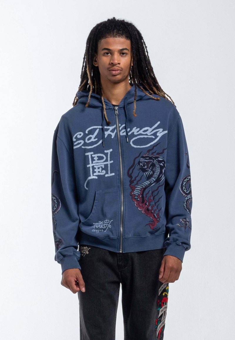 Navy zip-up hoodie with graphic designs of a serpent and octopus. Features a kangaroo pocket and contrasting logo text. Soft fabric texture.
