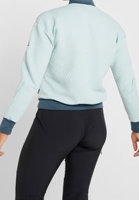 Světle modrá prošívaná bomber bunda s žebrovaným límcem a manžetami, s pevným námořnickým obrysem a texturovaným designem povrchu.