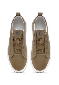 Zapatillas de cuero marrón con suelas blancas, con un acabado suave, detalles de costura y diseño de cordones. Logotipo visible en la lengüeta.