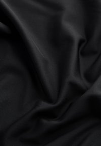 Tissu noir avec des plis doux et une surface lisse légèrement texturée montrée en gros plan.