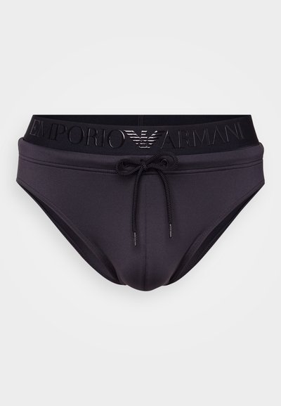 Melni peldkostīmi ar auklu un biezu jostu, uz kuras ir iegravēts Emporio Armani logos. Gluda, elastīga auduma, pieguļoša dizaina.