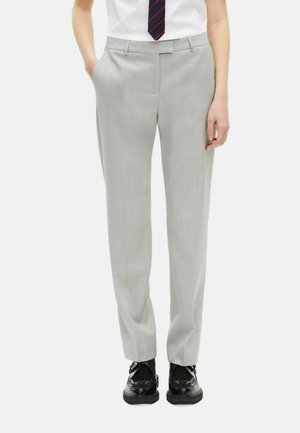 Lichtgrijze broek met een getailleerde pasvorm, zijzakken en een subtiele textuur. In combinatie met zwarte schoenen en een gestreepte stropdas.