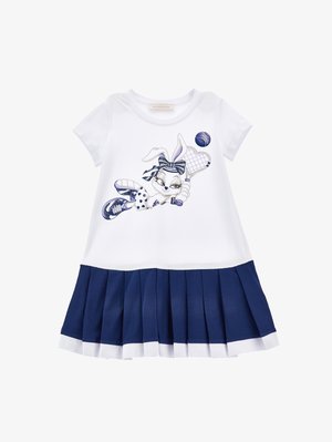 Vestito bianco a maniche corte con un coniglio blu dei cartoni animati che gioca a tennis. La gonna è di un blu navy con pieghe e un bordo bianco all'orlo.