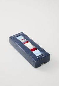 Set regalo di calzini per neonati Tommy Hilfiger in una scatola blu. Include tre paia: azzurro chiaro, bianco e rosso, con il marchio e i motivi ben visibili.
