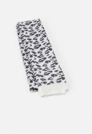 Écharpe blanche pliée avec un motif léopard noir et gris et des extrémités côtelées, placée sur un fond clair uni.