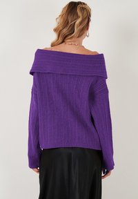 Maglione viola scollato con maniche lunghe, caratterizzato da una texture a coste e un fit morbido, in un design monocromatico.