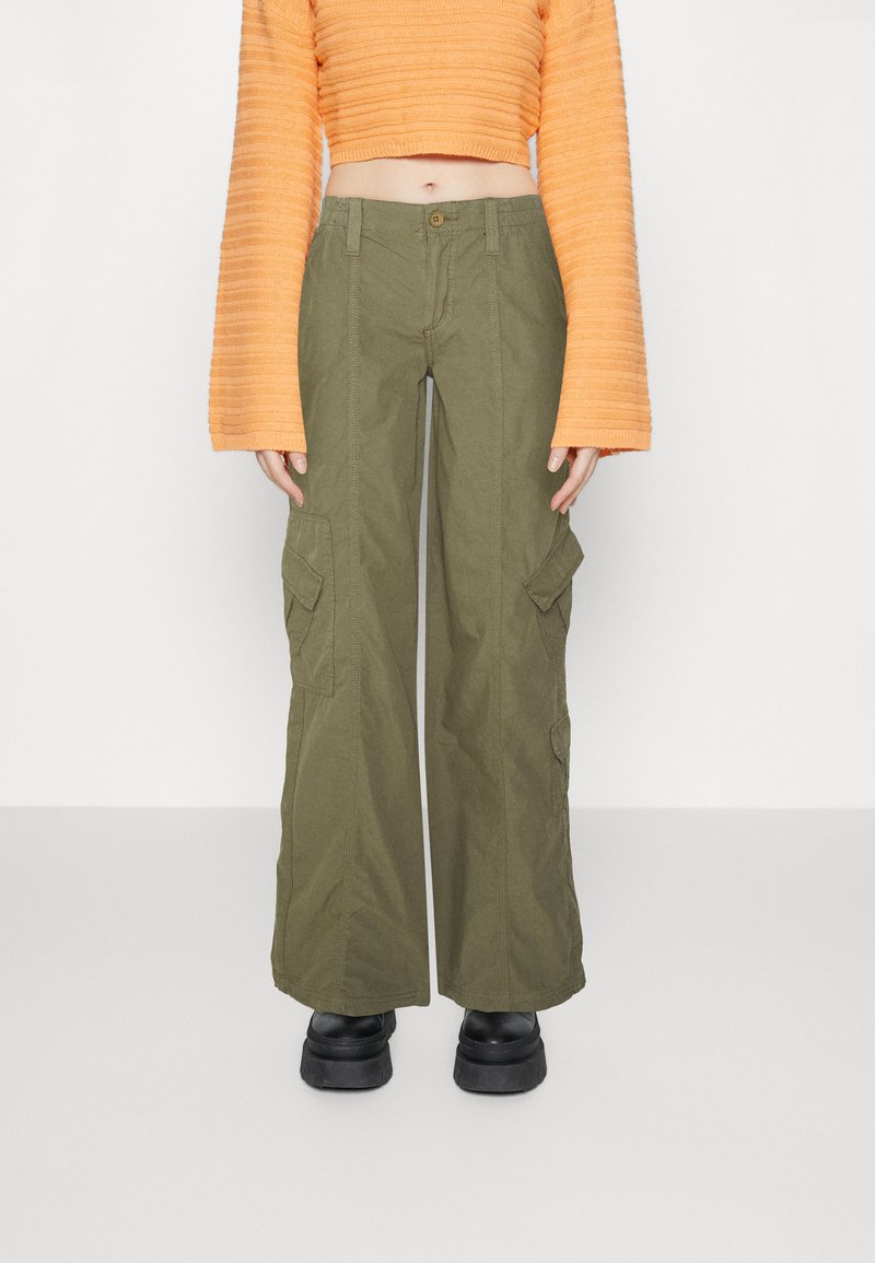 Ελαιόχρωμο cargo παντελόνι με φαρδιές μπατζάκια, φτιαγμένο από ανθεκτικό ύφασμα. Διαθέτει δύο μπροστινές τσέπες και κλείσιμο με κουμπί.