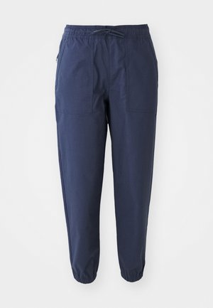 Námornícky modré jogger nohavice vyrobené z ľahkej tkaniny, s elastickým pásom, šnúrkou na stiahnutie a dvoma prednými vreckami. Elastické manžety na členkoch.