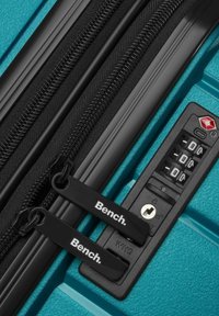 Türkise Reisetasche mit schwarzen Reißverschlüssen und Ziehlaschen, einem Kombinationsschlossmechanismus und einer strukturierten Oberfläche für besseren Halt und Langlebigkeit.