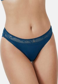 Bas de bikini bleu marine avec une bordure en dentelle au niveau de la ceinture, un tissu doux et un subtil accent métallique à l'avant.