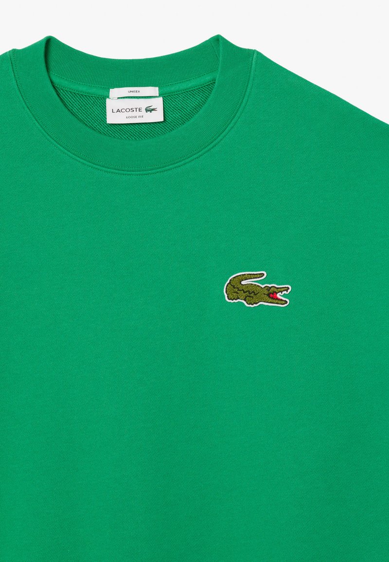 Sweatshirt vert en coton, avec une encolure ronde, un fit ample et un logo de crocodile brodé sur la poitrine gauche.