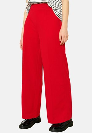 Wide-leg trousers in bright red fabric, featuring a high waist and smooth texture. Paired with black shoes and a striped top.