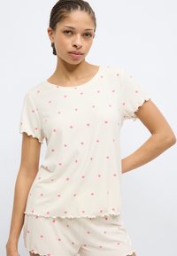 Σετ πυτζάμες με κοντά μανίκια από απαλό, ριμπ ύφασμα· κρεμ με μικρές ροζ καρδιές· με βολάν στα τελειώματα· άνετη εφαρμογή, ιδανικό για άνεση.