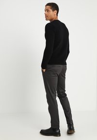 Black ribbed sweater, gray tailored pants, and black boots. The outfit features a fitted design with a smooth texture and minimal detailing.