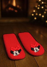 Red fleece slippers featuring a Minnie Mouse design, with a black bow and character face, textured surface, and rounded shape.