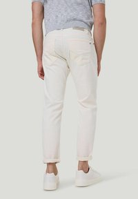 Witte jeans met opgerolde manchetten en een rechte pasvorm, met twee achterzakken en een gladde textuur, gecombineerd met witte sneakers.