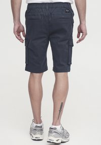 Marinefarbene Cargo-Shorts mit einem elastischen Bund, ausgestattet mit Seitentaschen, Gesäßtaschen und einer glatten Textur. Tragen sie mit grauen Sportschuhen.